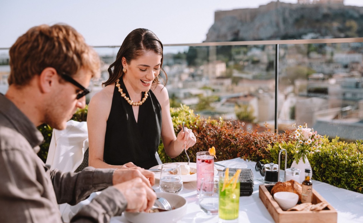 Couple enjoying a meal and refreshments on the rooftop restaurant of Electra Hotels during their Athens itinerary for 2 days. 