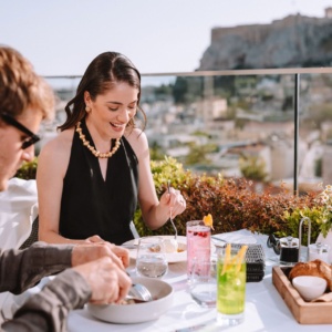 Couple enjoying a meal and refreshments on the rooftop restaurant of Electra Hotels during their Athens itinerary for 2 days. 