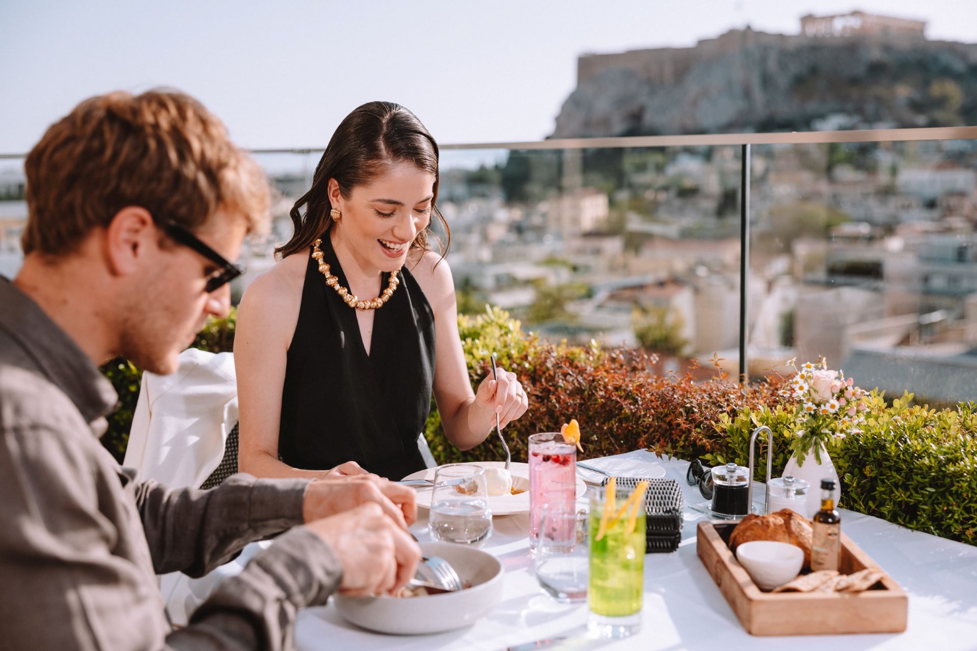 Couple enjoying a meal and refreshments on the rooftop restaurant of Electra Hotels during their Athens itinerary for 2 days. 