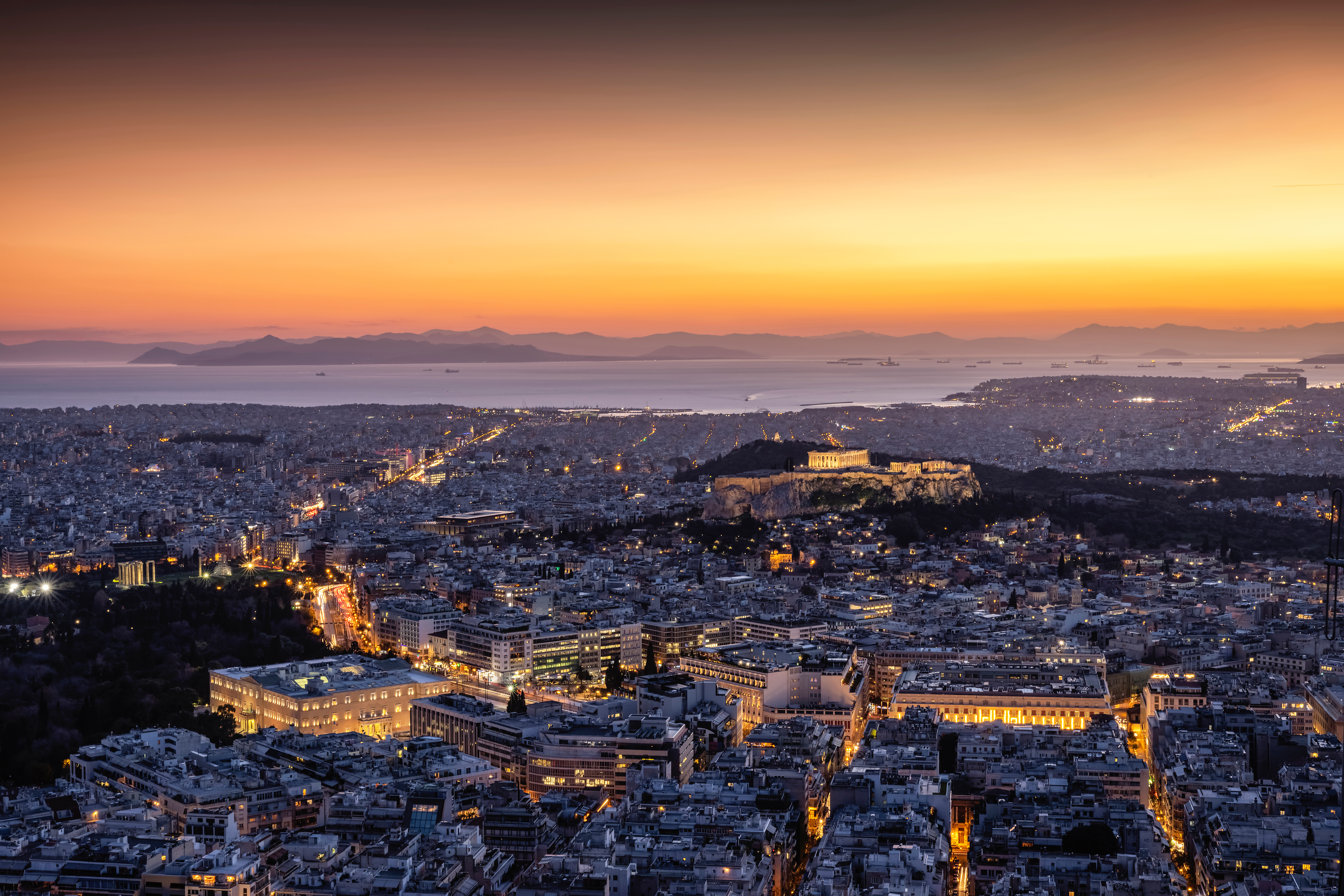 View over the illuminated skyline of Athens, Greece, with Parthenon Temple and the Acropolis and the busy streets around Syntagma Square during dusk