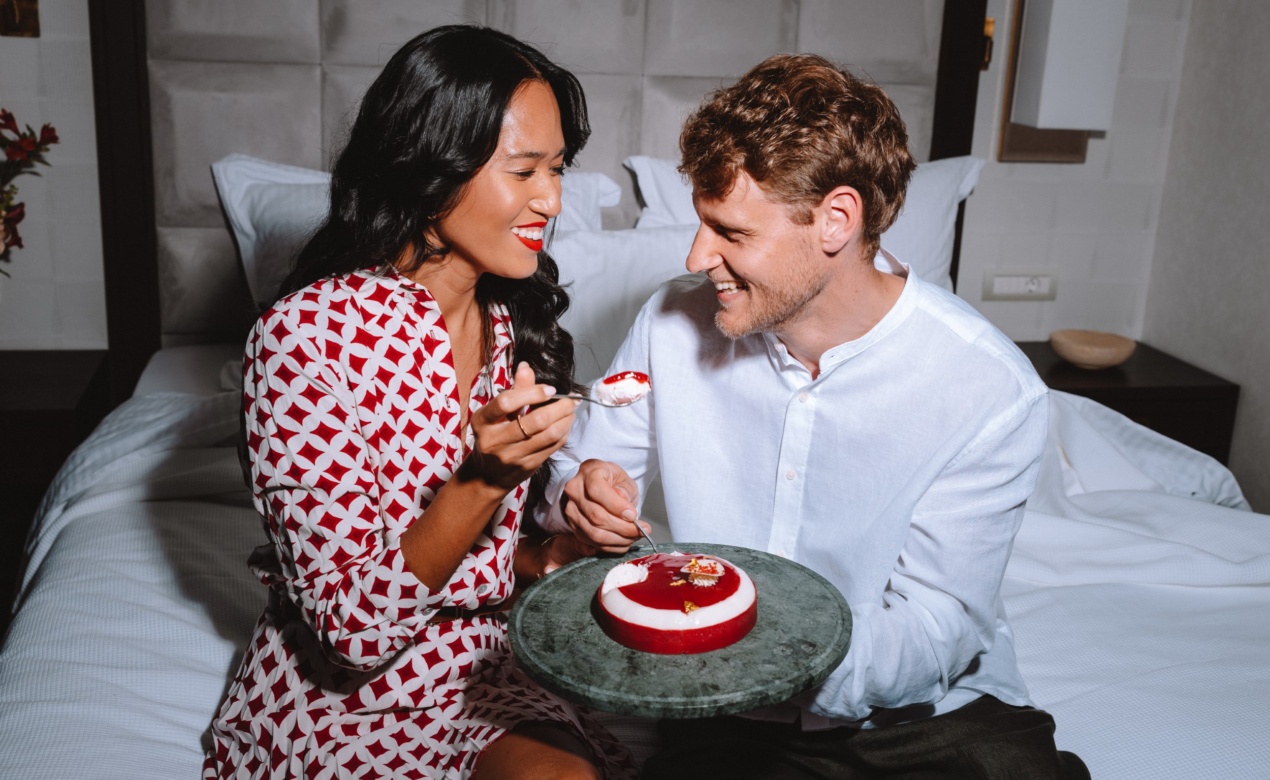 Elegant couple sharing a Valentine’s Day dessert in bed at Electra Hotels in Athens the perfect setting for romantic getaways for couples.