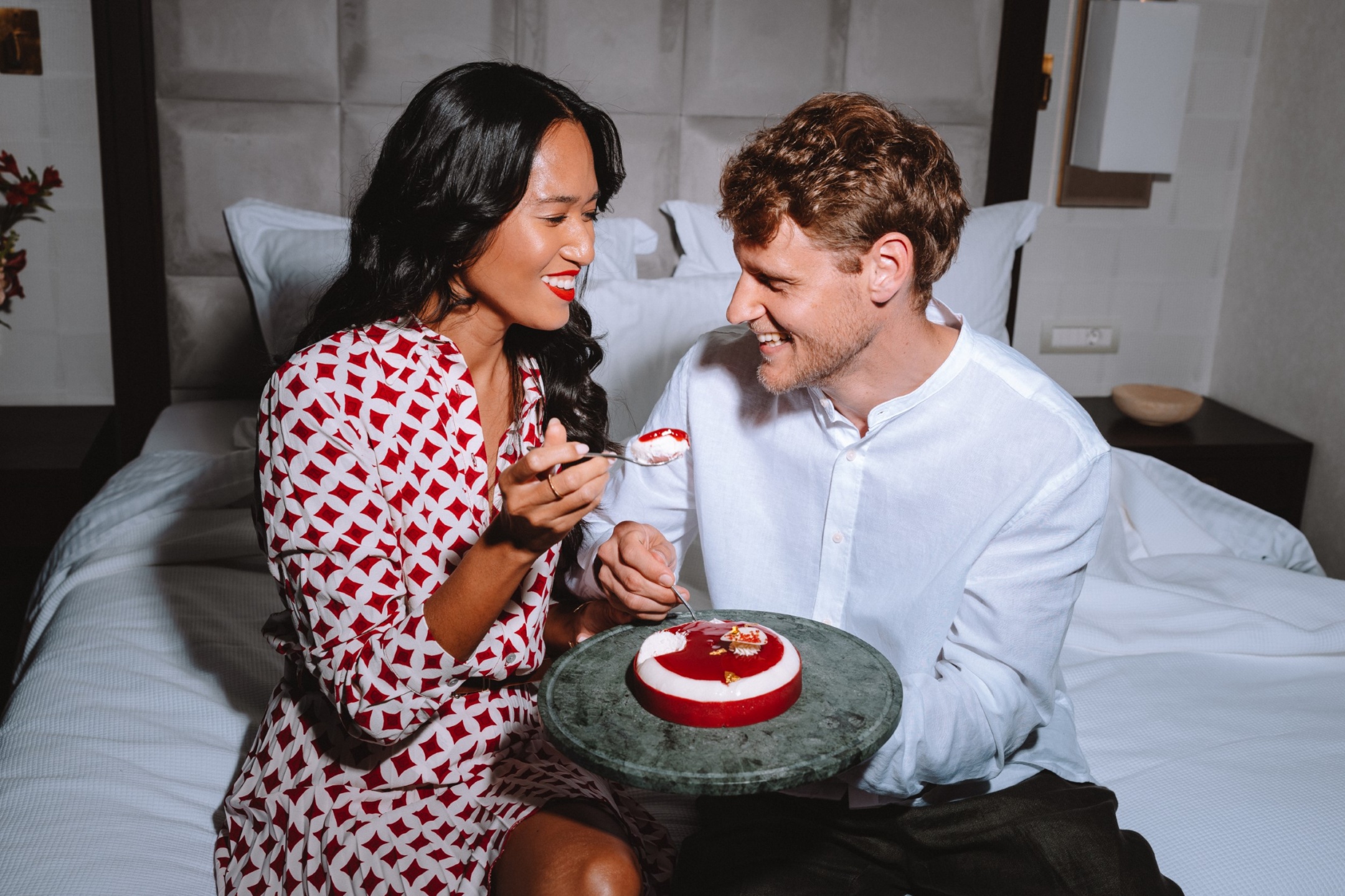 Elegant couple sharing a Valentine’s Day dessert in bed at Electra Hotels in Athens the perfect setting for romantic getaways for couples.