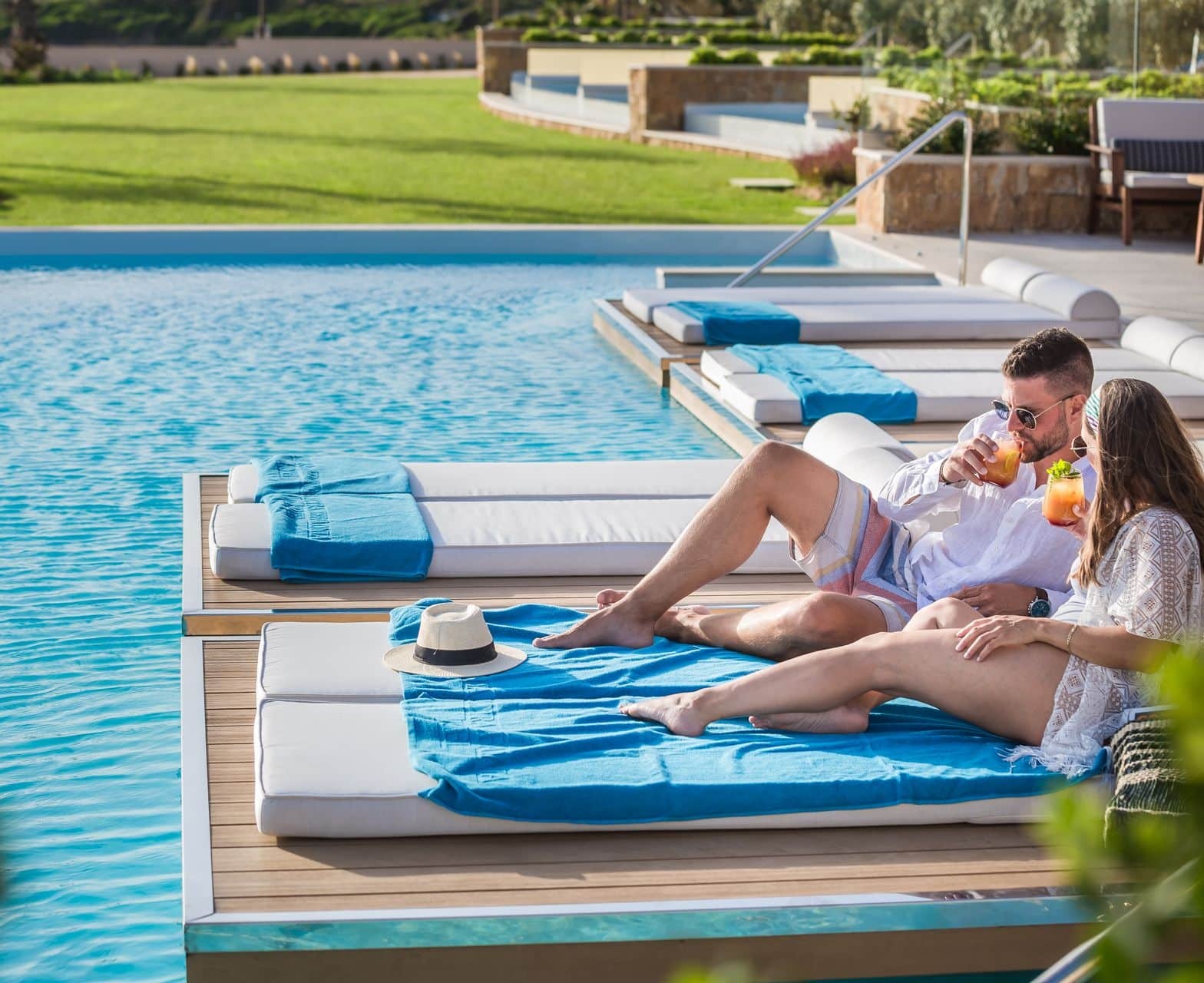 Guests enjoying a moment during their Kefalonia retreat with freshly prepared refreshment on the floating sunloungers at the pool of Electra Kefalonia Hotel & Spa.